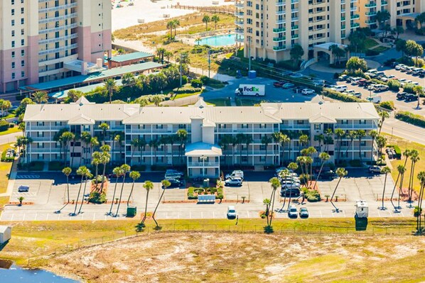 A hotel with a central courtyard, multiple parking lots, and a FedEx truck. - Sunny condo with pool, hot tub, pool views, balcony, & AC (Perdido Key)