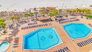 Et resort med flere swimmingpools, liggestole og en strand.