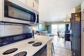 A modern kitchen with a microwave, stove, and refrigerator. - Oceanfront condo with beach access, pools & hot tubs (Panama City Beach)