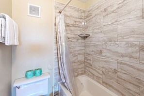 Een badkamer met een douche, toilet en marmeren tegels.