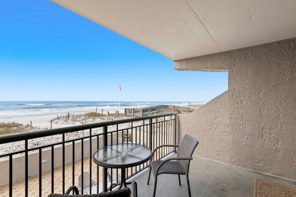 A balcony with a view of the beach, a round table, and two chairs. - 2nd-floor, updated condo with Gulf-front views - short drive to shopping (Fort Walton Beach)