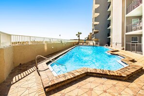 A swimming pool with a tiled deck, a metal ladder, and a white railing. - 2nd-floor, updated condo with Gulf-front views - short drive to shopping (Fort Walton Beach)