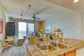 A modern kitchen with granite countertops, a double sink, and a ceiling fan. - Artsy beach condo with amazing views, bi-level pool & gym - near the beach (Panama City Beach)