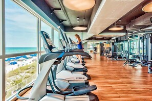A gym with treadmills, exercise equipment, and a view of the beach. - 2BR Gulf/beach-view with pool, hot tub, on-site dining, & private balcony (Panama City Beach)