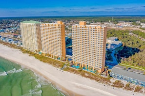 A high-rise hotel with multiple floors, a beachside location, and a pool area. - 2BR Gulf/beach-view with pool, hot tub, on-site dining, & private balcony (Panama City Beach)
