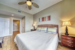 Ein Schlafzimmer mit einem Bett, zwei Nachttischen mit Lampen, einem Deckenventilator, einer Tür und einer kleinen Bank.