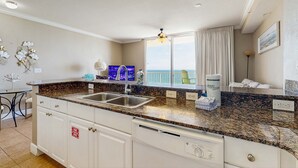 Una cocina moderna con encimeras de granito, un lavabo doble y vista al océano.