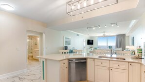 Une cuisine moderne avec des meubles blancs, un lave-vaisselle et un grand îlot central doté d’un évier.