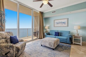 Une pièce avec un balcon, un canapé, une chaise, une petite table et une lampe.