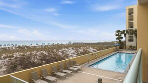 A pool area with lounge chairs and a view of the beach. - Oceanfront Condo with Shared Pool & Hot Tub, Ocean View, & Private Washer&Dryer (Fort Walton Beach)