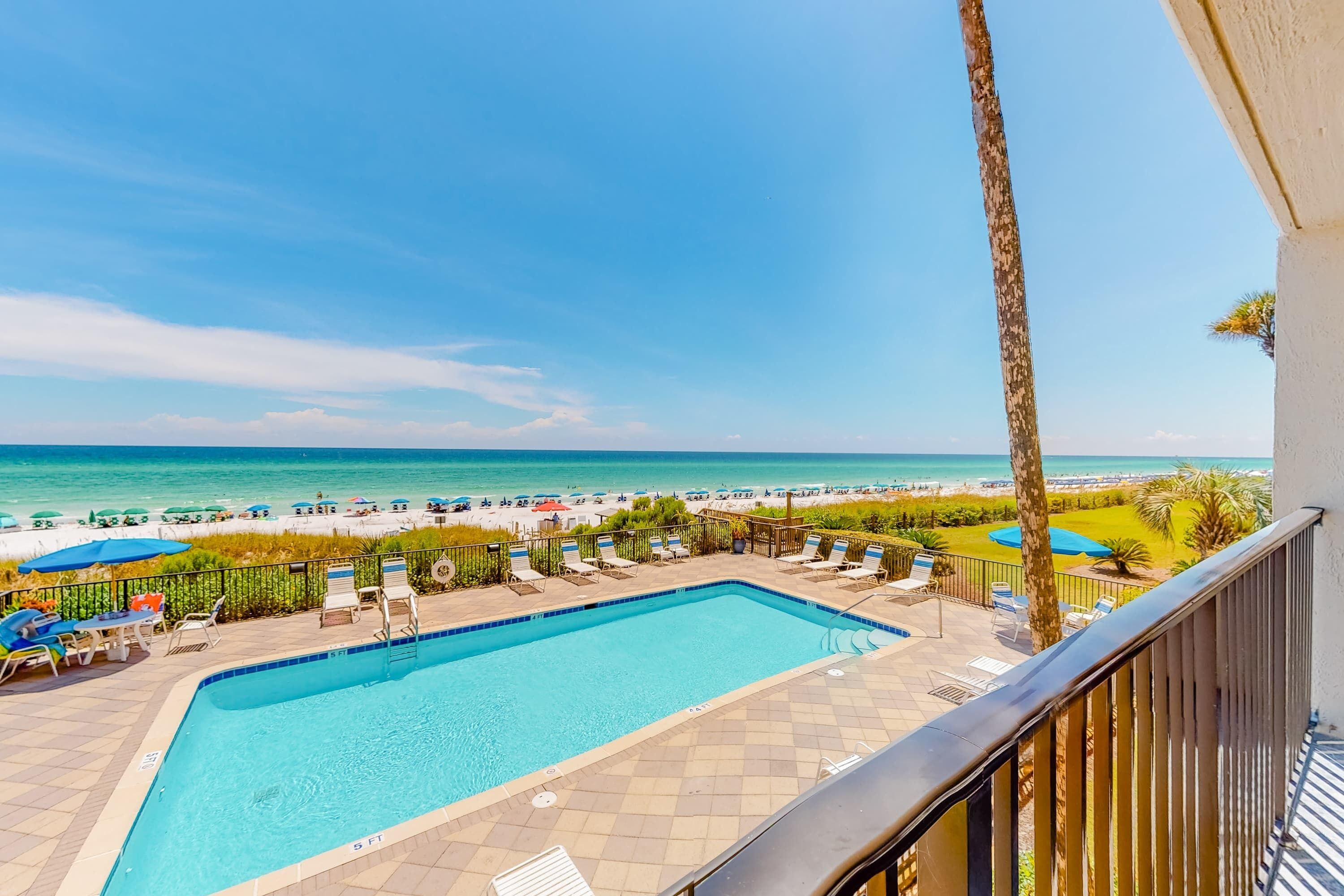 A pool area with a view of the beach and ocean.
