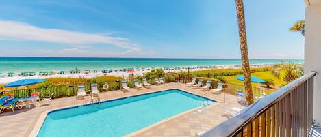 A pool area with a view of the beach and ocean.