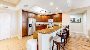 Una cocina amplia con armarios de madera, encimera de granito y una isla central con taburetes de bar.
