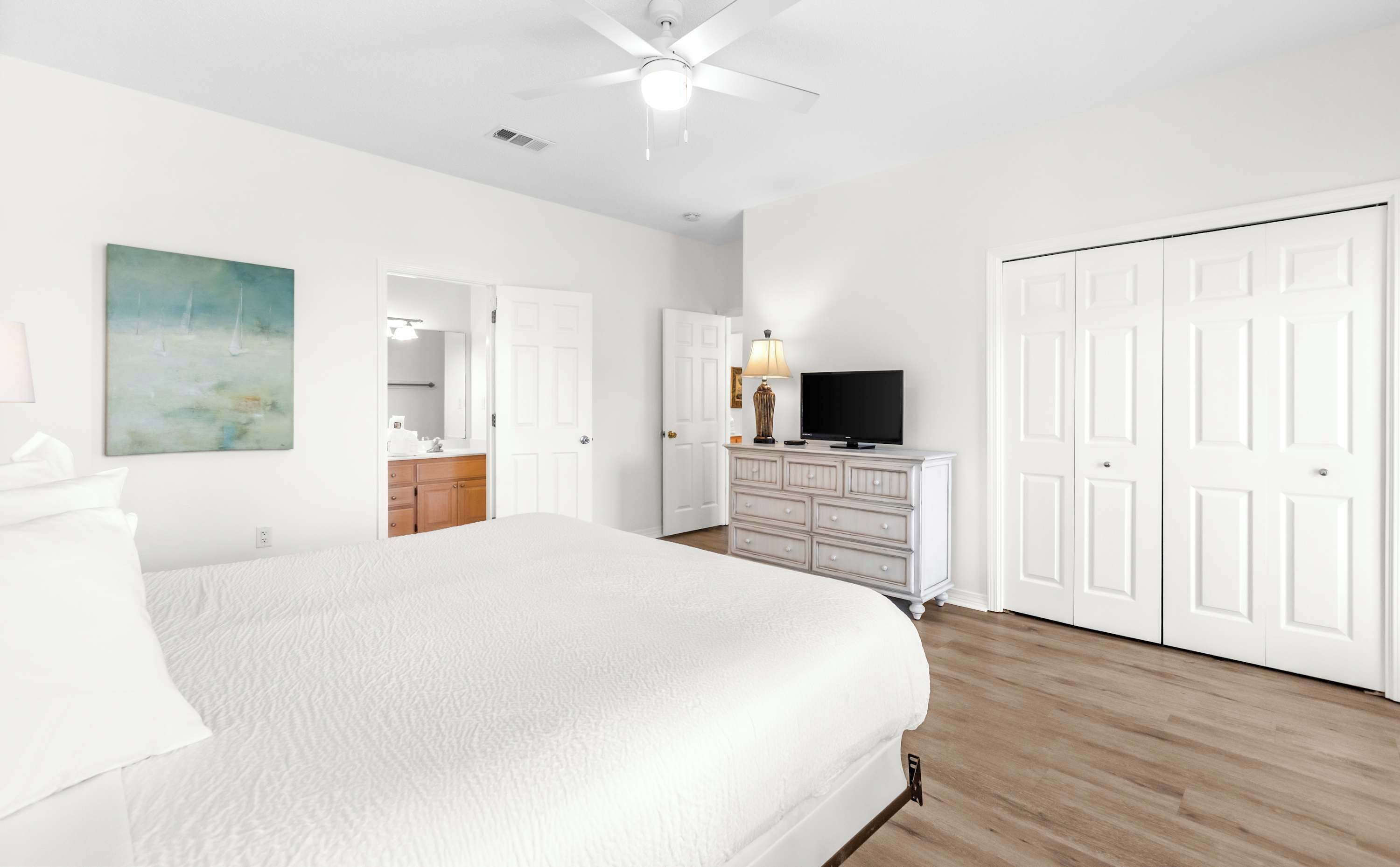 A bedroom with a bed, a dresser, a television, and a closet.