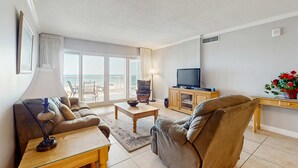 Un salon comprenant un canapé, une table basse, un téléviseur et un balcon avec vue.