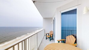 Un balcon avec vue sur l’océan, des chaises en bois et une table.
