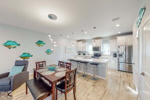 A modern kitchen with stainless steel appliances, a central island, and bar stools.