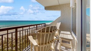 A balcony with a view of the ocean, featuring two Adirondack chairs and a small table. - 4th-floor, bright, Gulf-front condo with views - close to entertainment (Fort Walton Beach)