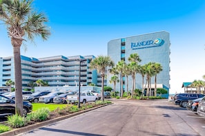 Ein Hotel mit einer großen Schrifttafel, auf der "ELANDER BEACH RESORT & CONDOMINIUMS" steht, und einem Parkplatz mit mehreren Autos.