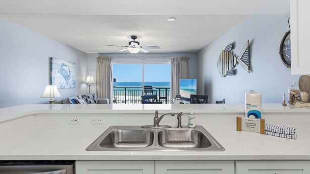 A kitchen with a view of the beach, a ceiling fan, and a dining area with a view. - Gulf front condo w/ beach setup included - near entertainment (Fort Walton Beach)