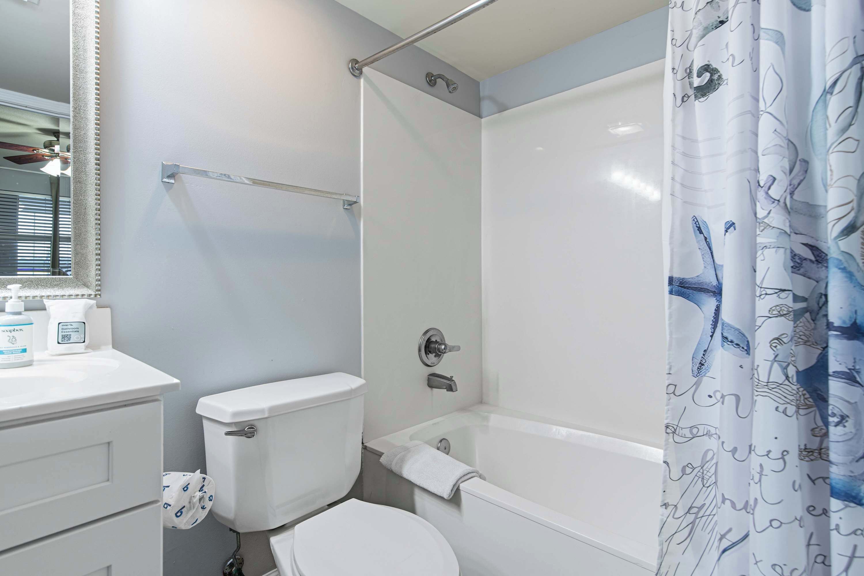 A bathroom with a toilet, a bathtub, a shower, and a vanity with a mirror.