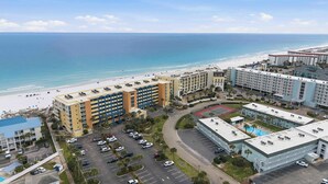 A hotel with multiple buildings, a beach, and a parking lot. - Gulf front condo w/ beach setup included - near entertainment (Fort Walton Beach)