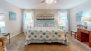 A bedroom with a bed, two bedside tables, a desk, and a chair. - Home with kitchen, patio, playground, central AC, & W/D (Pensacola)