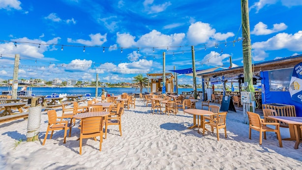 A beachside café with wooden tables and chairs, string lights, and a view of the ocean. - Home with kitchen, patio, playground, central AC, & W/D (Pensacola)