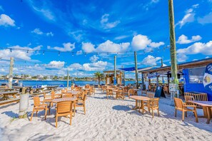 A beachside café with wooden tables and chairs, string lights, and a view of the ocean. - Home with kitchen, patio, playground, central AC, & W/D (Pensacola)