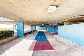 An indoor parking area with concrete pillars, a blue wall, and a red carpet with a hopscotch pattern. - Gulf front condo with free WiFi, washer&dryer, shared pool, & beach access (Fort Walton Beach)