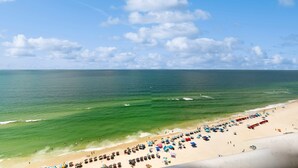 Ein Strand mit aneinandergereihten Sonnenschirmen und Liegestühlen, ein sandiger Uferstreifen und der Ozean.