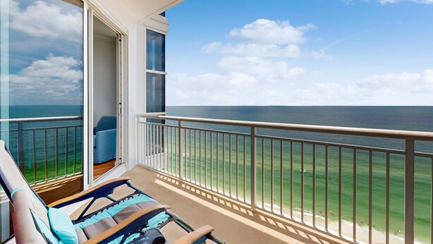 Ein Balkon mit Blick auf das Meer, ein Stuhl und eine Tür zu einem Innenbereich.