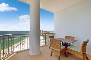 A balcony with wicker furniture and a view of the beach and ocean. - 18th-floor condo with amazing views, beach access, pools & gym (Perdido Key)