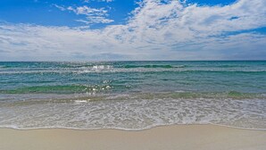Een strand met helderblauw water en een zandstrand.