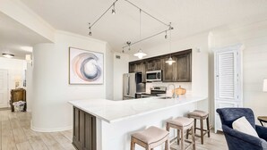 Een moderne keuken met een wit kookeiland, donkerhouten kastjes en een groot abstract schilderij.