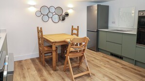 Una cocina moderna con una mesa y sillas de madera, un refrigerador integrado y un espejo instalado en la pared.