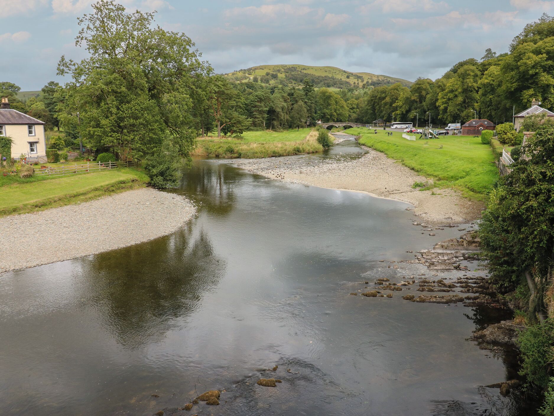 A river flowing through a rural landscape with houses on the banks.