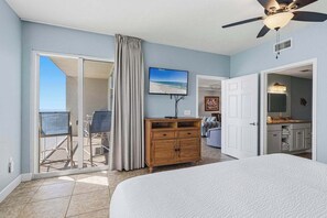 Ein Hotelzimmer mit Bett, einem Holzschrank, einem Fernseher und einem Balkon mit Blick auf den Strand.
