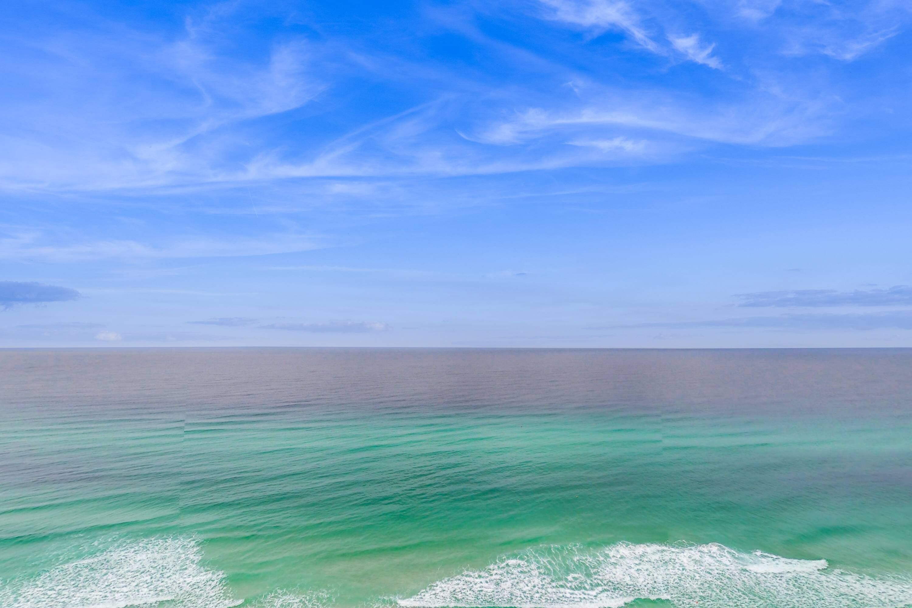 A view of the ocean with clear blue skies and calm waters.