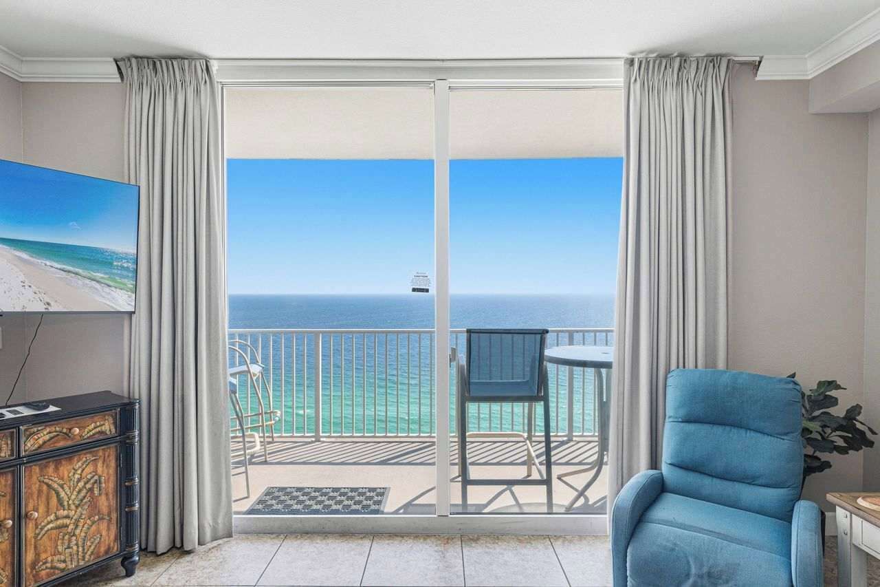 Ein Zimmer mit Meerblick, ein Balkon mit einem Stuhl und ein Fernseher auf einem Schrank.