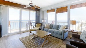 Ein geräumiges Wohnzimmer mit einer großen Couch, einem Couchtisch und einem Balkon mit Meerblick.