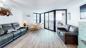 Ein modernes Wohnzimmer mit zwei Ledersofas, einem Esstisch mit Stühlen und Meerblick durch große Fenster.