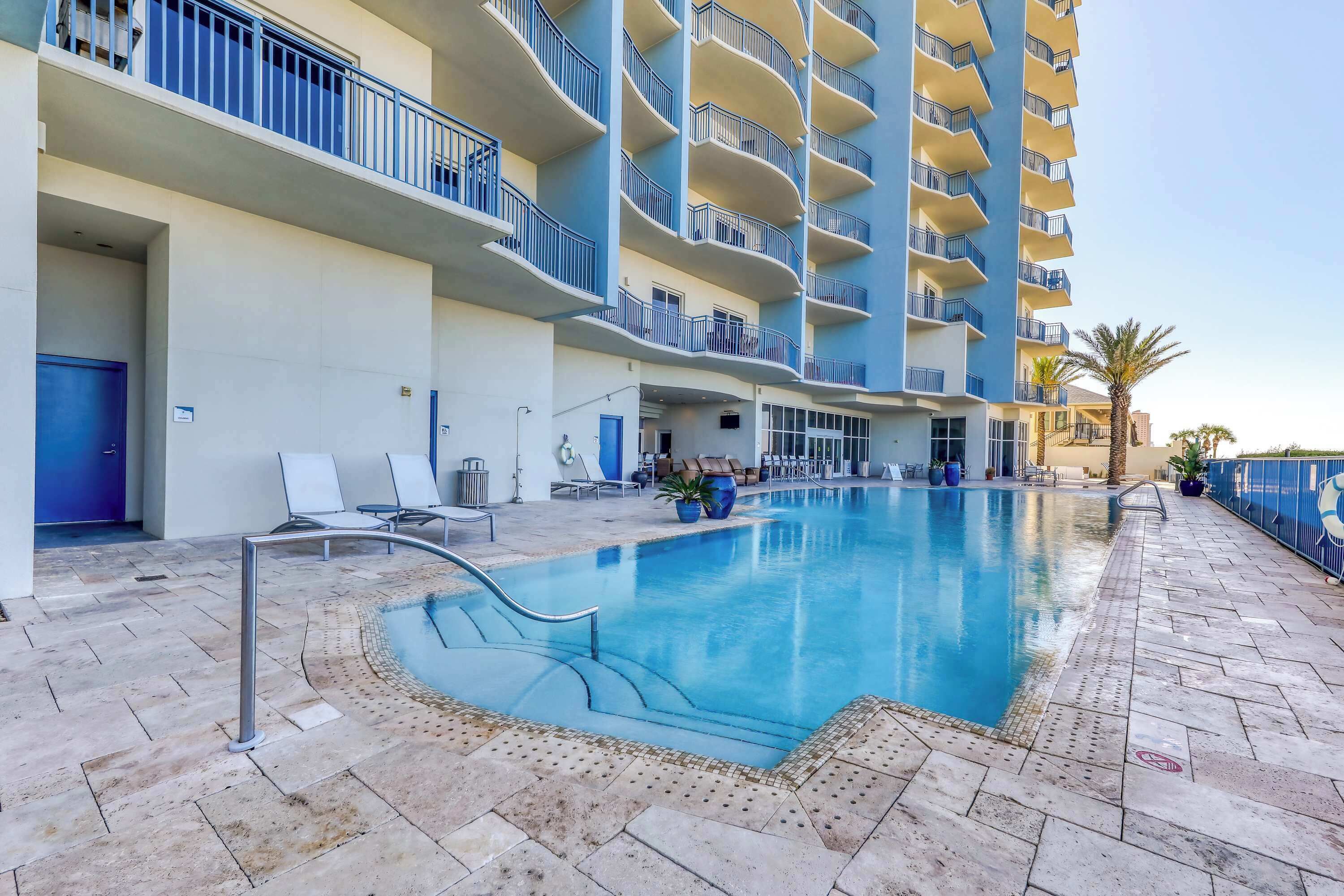 Ein Hotel mit Schwimmbad, mehreren Balkonen und Liegestühlen.
