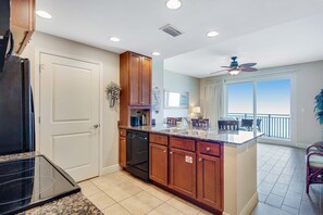 A kitchen with wooden cabinets, a dishwasher, and a large island with a sink. - Beachfront condo with incredible views, pool, hot tub & fitness center (Panama City Beach)