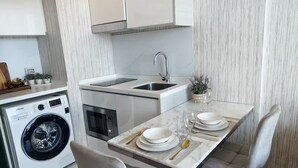 A compact kitchen with a washing machine, a built-in oven, and a sink. - 1 BR 5mins to beach Sea view Riviera Wongamat (Muang Pattaya)