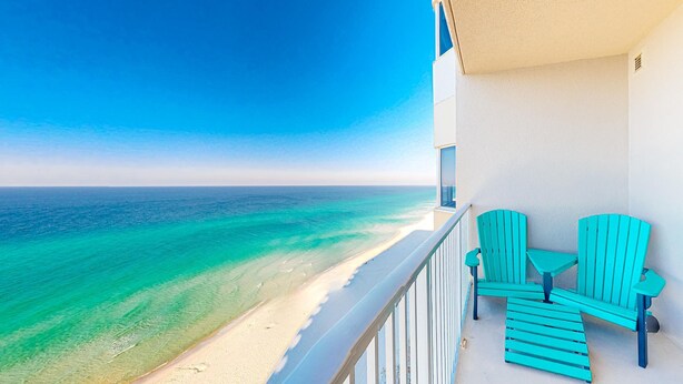 A balcony with turquoise chairs and a small table overlooking a beach with clear turquoise water. - Inviting gulf-front condo w/ beach service, pools, hot tubs & fitness center (Panama City Beach)