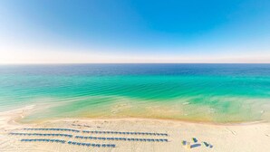 An aerial view of a beach with rows of blue umbrellas and a clear blue sky. - Inviting gulf-front condo w/ beach service, pools, hot tubs & fitness center (Panama City Beach)