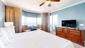 A hotel room with a large bed, a wooden dresser, a television, and a balcony with a view of the ocean. - Inviting gulf-front condo w/ beach service, pools, hot tubs & fitness center (Panama City Beach)