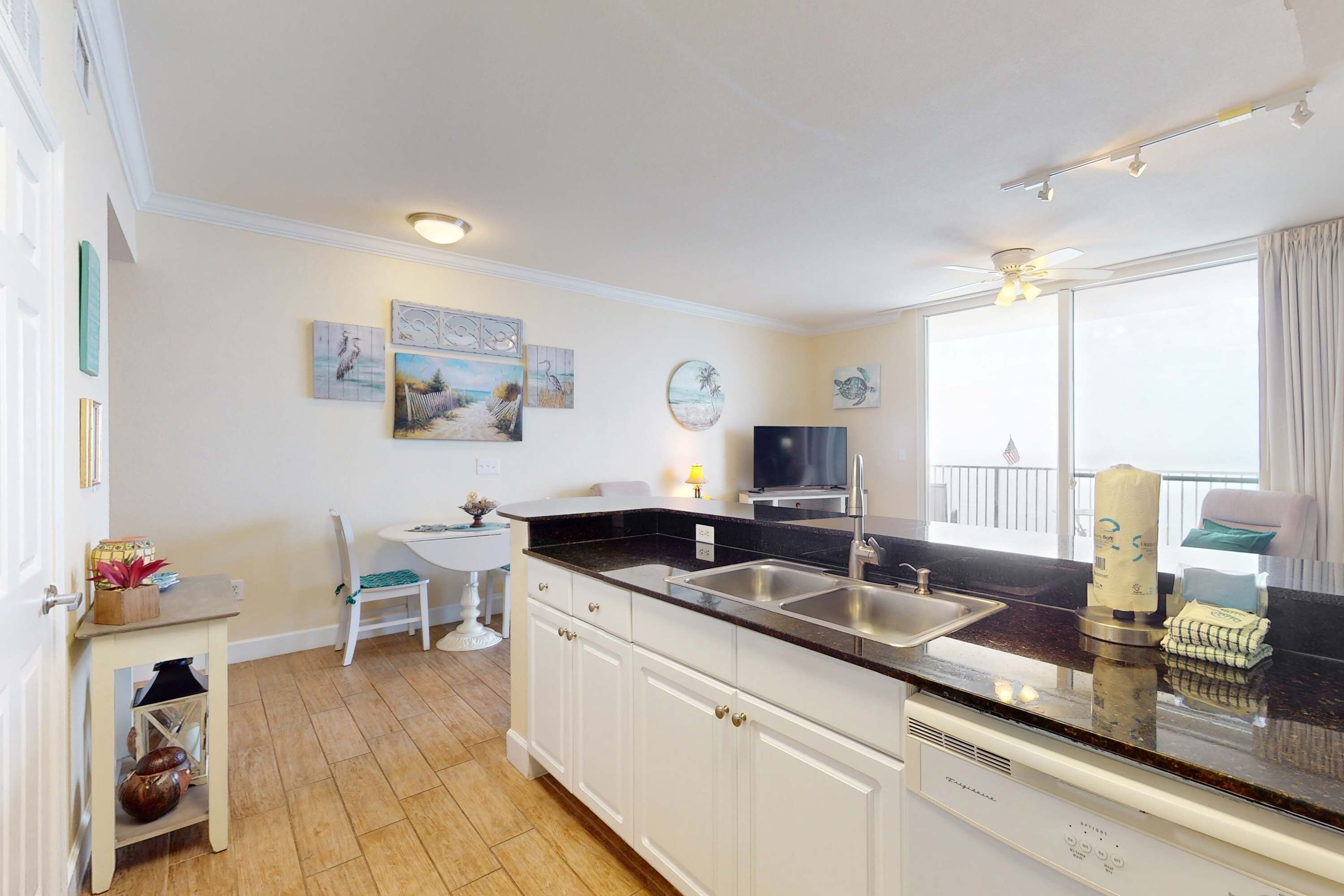 A kitchen with white cabinets, a black countertop, and a window with a view of the outside.