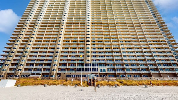 A tall, multi-story hotel with a uniform facade and balconies. - 22nd-floor beachfront condo with Gulf views, hot tub, pools, sauna, gym, balcony (Panama City Beach)